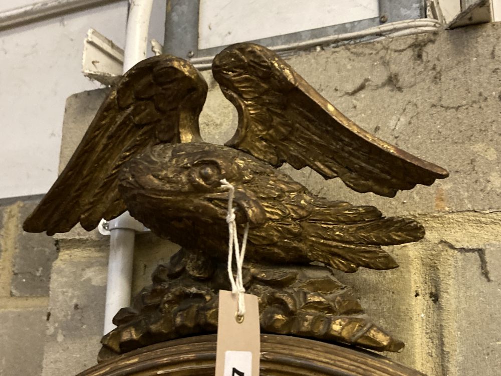 A Regency carved giltwood and gesso circular convex wall mirror with eagle pediment, height 69cm, width 50cm